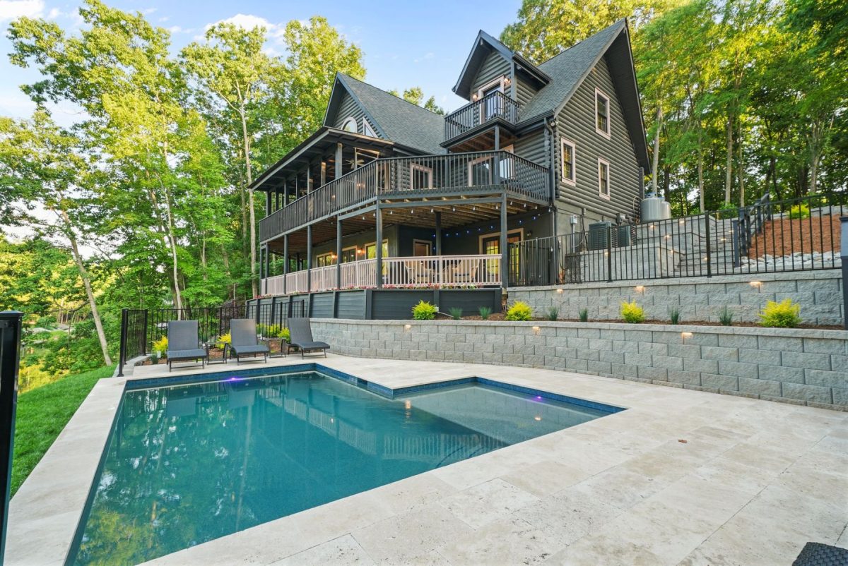 DSC09795 | Southern Charm Retreats Modern gray two-story house with a large wooden deck overlooking a backyard pool.